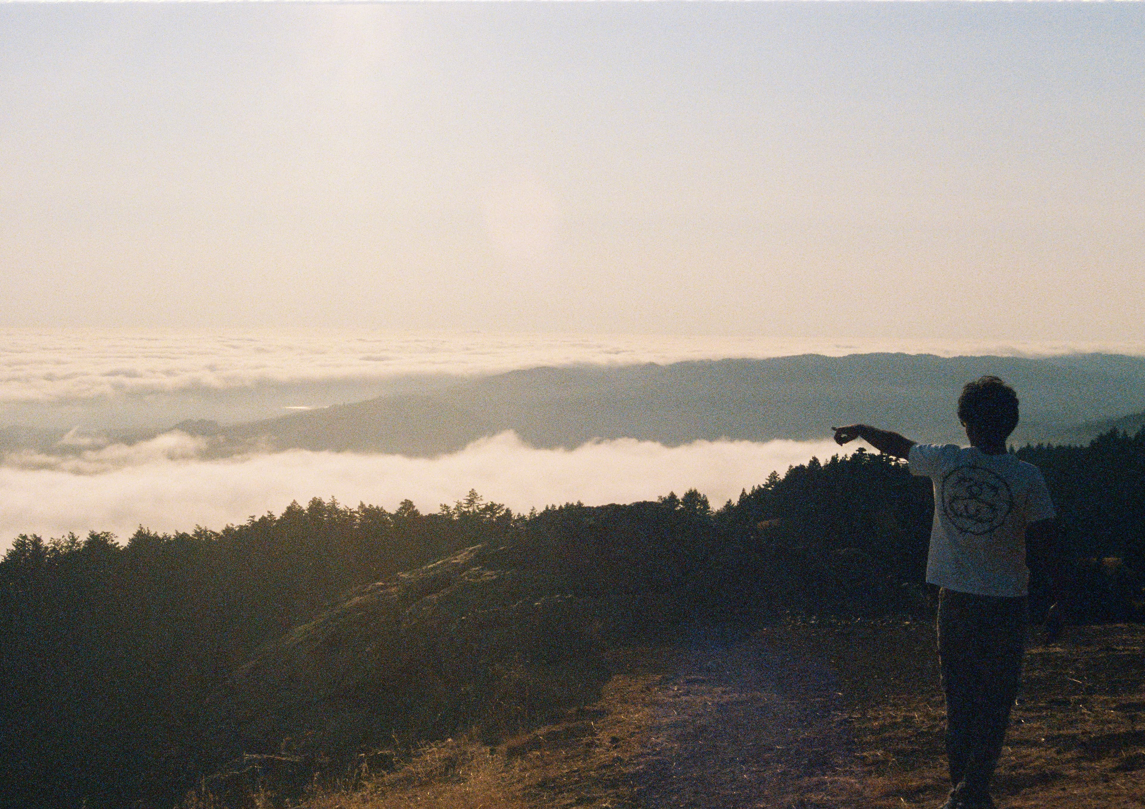Pointing out over a sea of fog from a ridgeline at golden hour